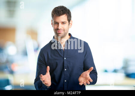 Portrait of smiling young businessman standing with his arms raised at the office.