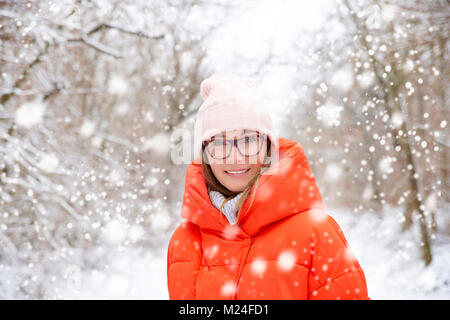 Close-up portrait of middle aged woman wearing hat while standing outdoor and enjoys snowfall. Stock Photo