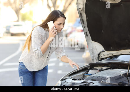 Worried driver with car breakdown calling insurance on the street Stock Photo