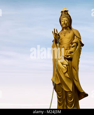 Bronze statue of Guanyin, female Buddha, the Goddess of Compassion, cradles a baby in her hand, Mother Goddess. Also know as Guan Yin, Kuan Yin, Kanno Stock Photo