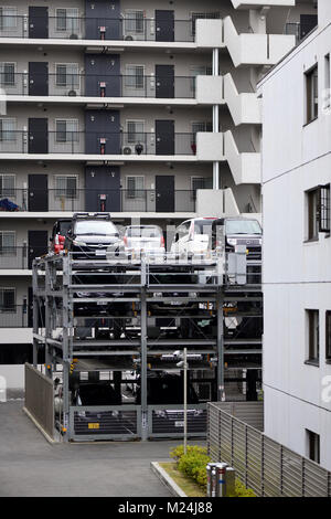 Cars parked in a multi-level vertical three-storey automated parking lot with a lift by an apartment building in Kyoto, Japan 2017 Stock Photo