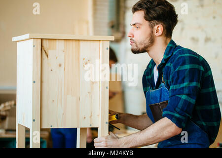 carpenter testing wood plank evenness at workshop Stock Photo