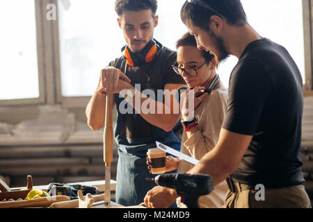 Carpenter Training Female Apprentice To Use Plane Stock Photo