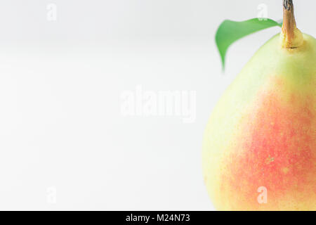 Single Ripe Organic Pear in Pastel Green Yellow Red Colors with Stem Leaf on White Table. Elegant Minimalist Japanese Style. Creative Image for Social Stock Photo