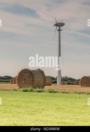 An image showing a hay bale in the foreground and a wind turbine behind at Eye Kettleby Lakes, Melton Mowbray, Leicestershire, England, UK Stock Photo