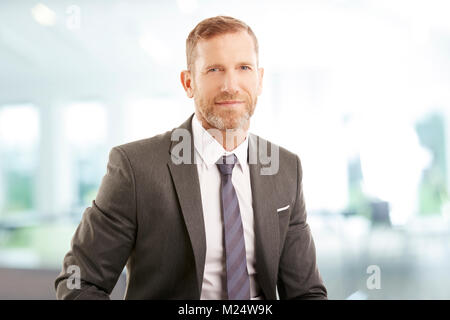 Middle aged financial director businessman sitting at office and looking at camera. Stock Photo