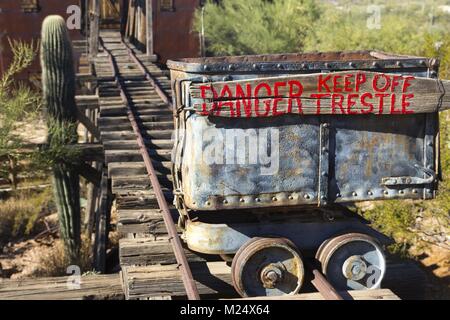 Isolated Mine Cart with Red Paint Danger Trestle Sign on Old Rusted Rail Tracks in Arizona Desert near Phoenix Stock Photo