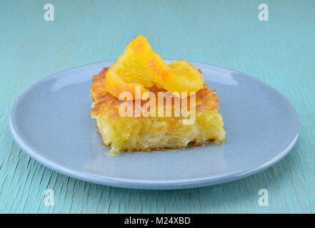 Piece of orange pie in plate with orange twist slice on top Stock Photo