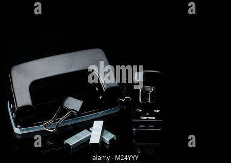 Black stapler, staples, paperclip and punch on dark background with copy space. Office equipment concept Stock Photo