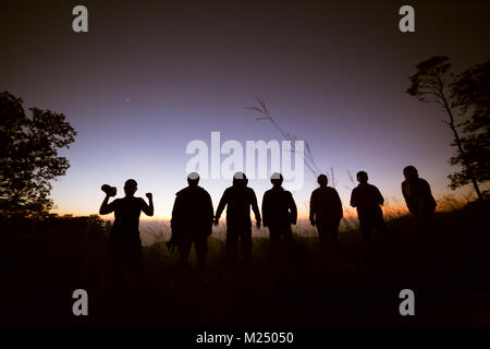 Happy friends, family jumping together in a circle having fun and expressing emotions of joy, freedom, success. Silhouettes on sunny sky Stock Photo