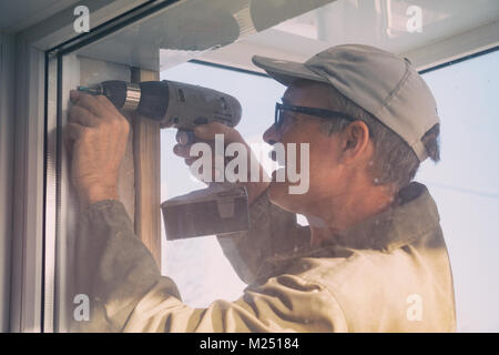 Carpenter in glasses working with a drill. Stock Photo