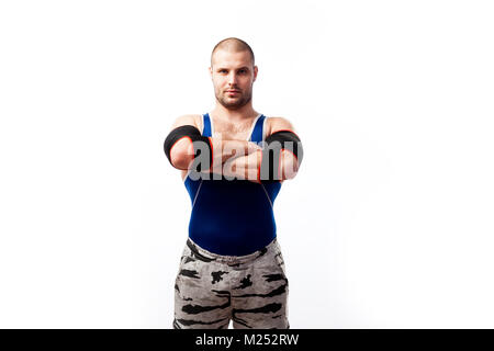 Young sportive man in blue tights and black elbow stands and holds his hands cross-over on his chest on a white isolated background Stock Photo