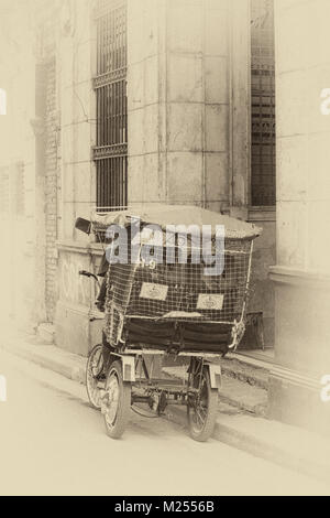 Daily life in Cuba - Local man riding bicitaxi bicycle taxi at Havana, Cuba, West Indies, Caribbean - back rear view toned to give aged effect look Stock Photo