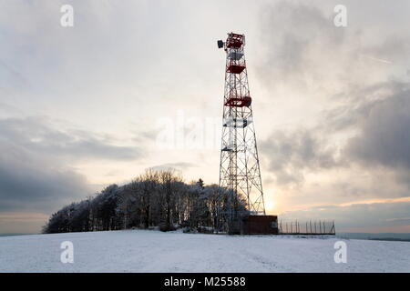 Transmitters and aerials on telecommunication tower, sunset in snowy country Stock Photo