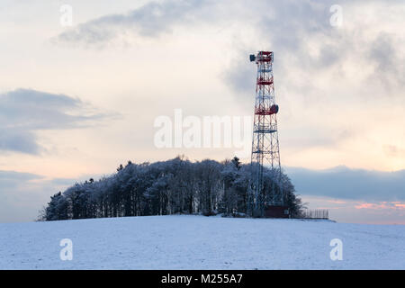 Transmitters and aerials on telecommunication tower, sunset in snowy country Stock Photo