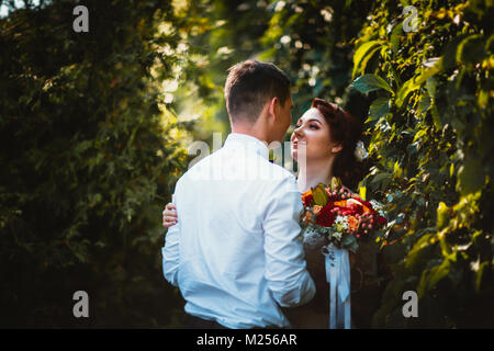 The bride and groom in the foliage of trees Stock Photo