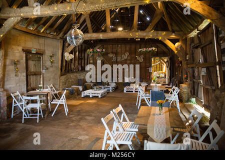 Barn decorated for special occasion with glitter ball, string lights, tables and chairs Stock Photo