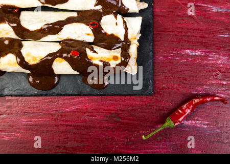 Mexican chicken enchiladas with chili chocolate salsa mole poblano. Tradiional Latin American cuisine. Stock Photo