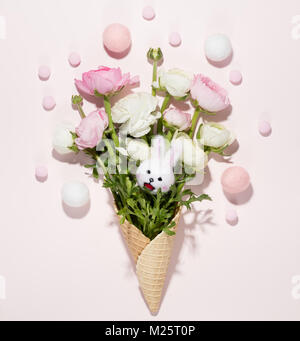 Buttercup flowers in the waffle cone with easter eggs on pink background Stock Photo