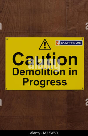 Caution demolition in progress warning sign, with exclamation mark and logo of the demolition company matthews