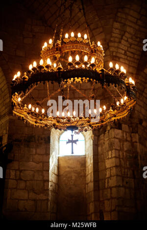 A hanging candelabra and crucifix in the church of Saint Jean-Baptiste in the medieval village of St Jean de Cole in the Dordogne France Stock Photo