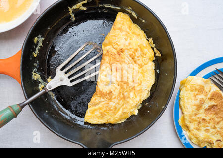 Omelette with melted cheese in a frying pan on a light background Stock Photo