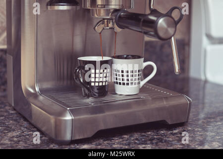 Home espresso machine on kitchen countertop making two cups coffee. Stock Photo