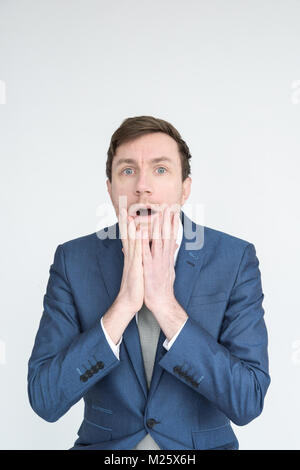 Portrait of a well dressed man in a suit looking shocked and distraught in to camera. Isolated on a white background Stock Photo