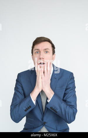 Portrait of a well dressed man in a suit looking shocked and distraught in to camera. Isolated on a white background Stock Photo