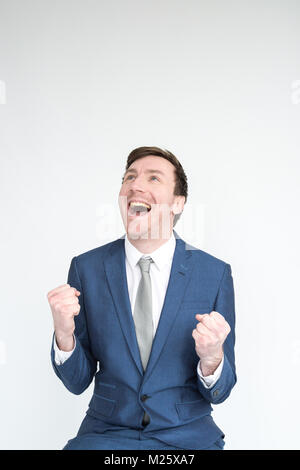 A very excited, well dressed man in a suit punches the air in triumph at an achievement. portrait isolated on white background Stock Photo