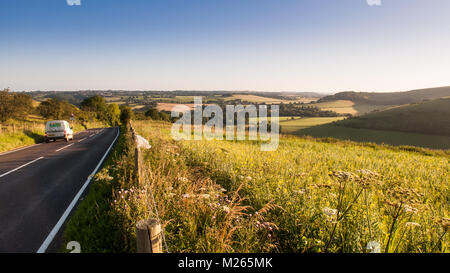 Traffic on the C13 Melbury Abbas road crosses the chalk grassland of Cranborne Chase between Blandford Forum and Shaftesbury in Dorset. Stock Photo