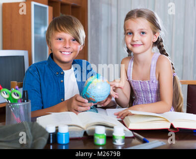 Portrait of happy children with textbooks and notes in livingroom at home Stock Photo