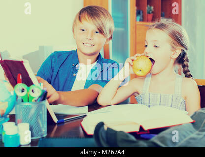 Portrait of positive children with textbooks and notes in livingroom Stock Photo