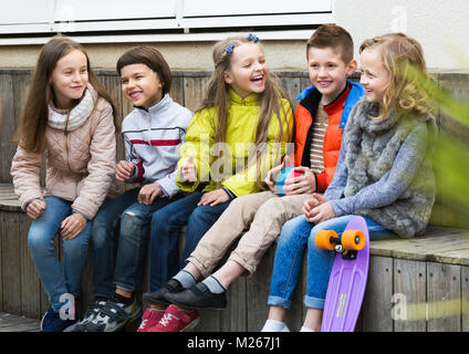 Attractive little boys and girls sharing secrets as talking outdoor Stock Photo