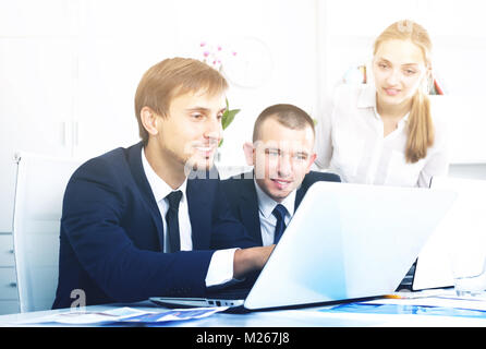 Three smiling coworkers working on computers together in company office Stock Photo