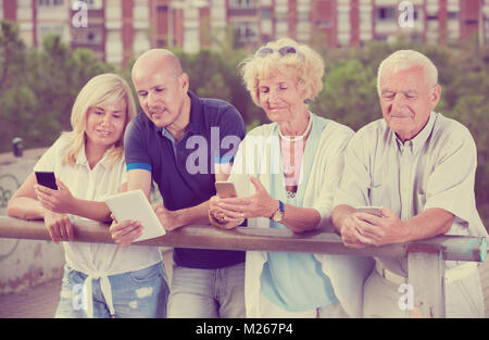 Four positive people texting in smartphones in the garden Stock Photo