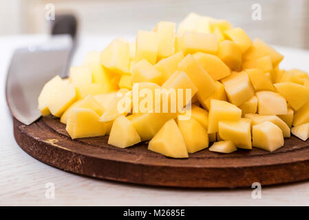 Pile of potato cut in pieces on wooden board Stock Photo