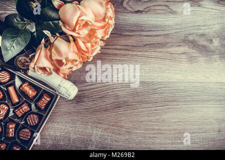 Champagne in a bottle, box of chocolates and roses  on wooden table. Valentines day celebration concept. Copy space.View from above Stock Photo