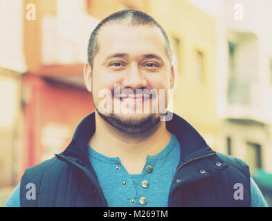Handsome smiling young man with a beard in a blue jacket and a blue vest Stock Photo