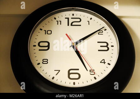 Round clock with white clock face and black body Stock Photo