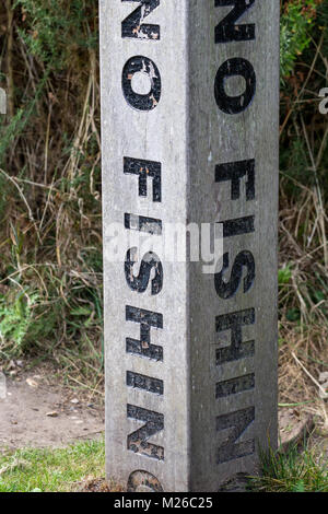 A vertical no fishing warning message on a concrete post Stock Photo