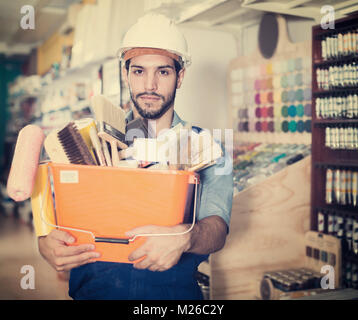 Active workman holding basket with picked tools in paint store Stock Photo