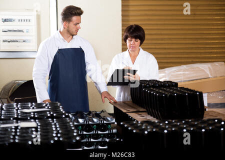 Hardworking employees checking number of wine bottles at sparkling wine factory Stock Photo