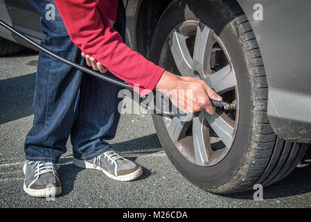 Driver checking air pressure and filling air in a tire of a car Stock Photo