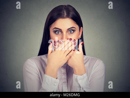 Young woman covering mouth looking terrified because of prohibition to talk. Stock Photo