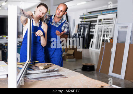 Team of two workers in blue overalls assembling pvc windows at factory Stock Photo