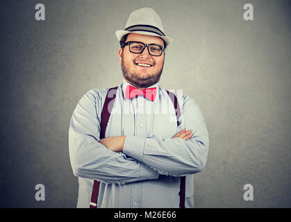 Young happy man posing in eccentric outfit smiling at camera on gray. Stock Photo