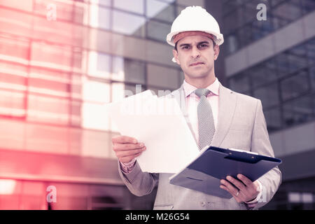 Businessman holding folder with documents and attentively reading Stock Photo