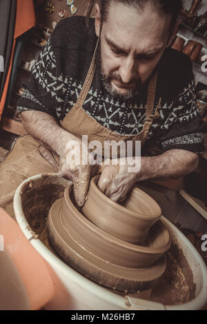 elderly man making pot using pottery wheel in studio Stock Photo