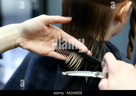 Le Mans (western France). 2014/12/03. Young woman, hairdressing apprentice, cutting a woman's hair. Stock Photo